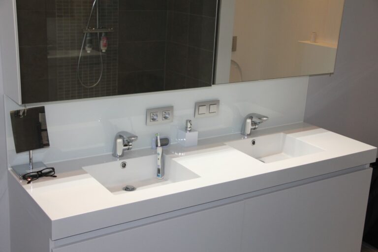 een glazen spatwand achter de lavabo's beschermt de muren
