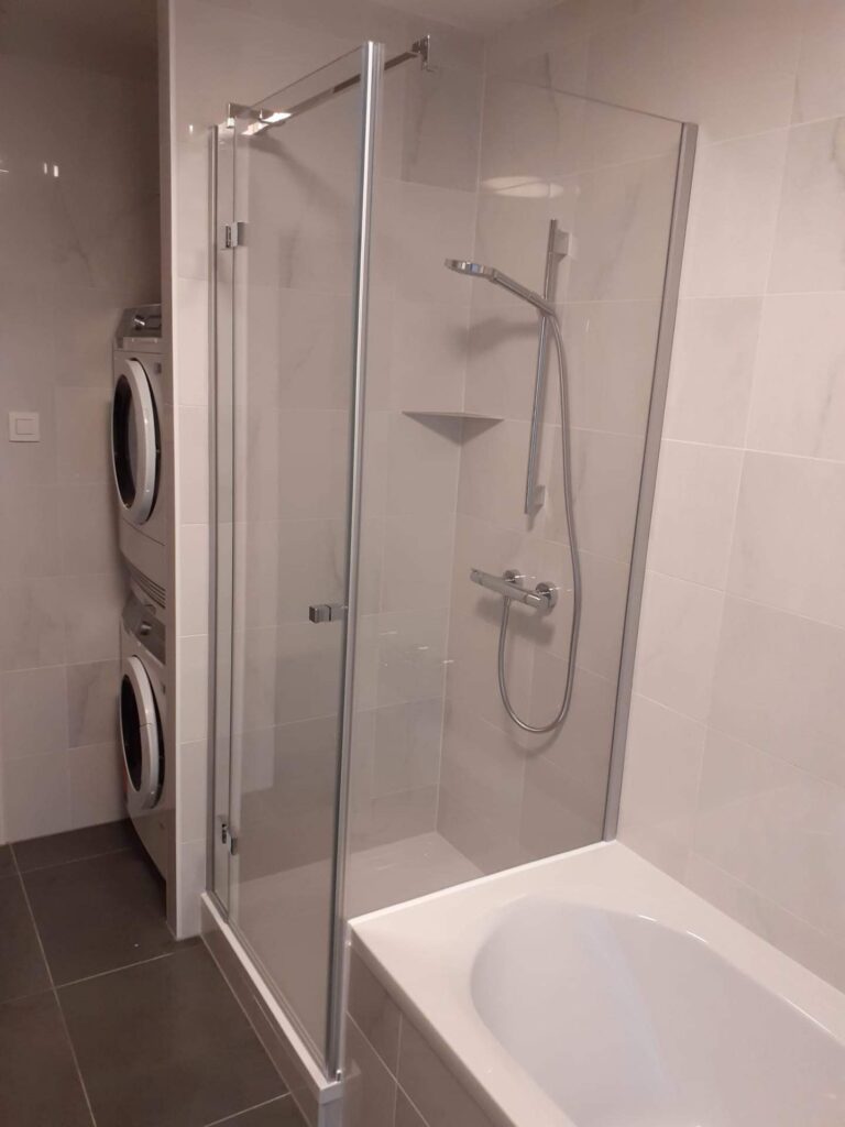 douchecabine met een wand naast het bad en een douchedeur