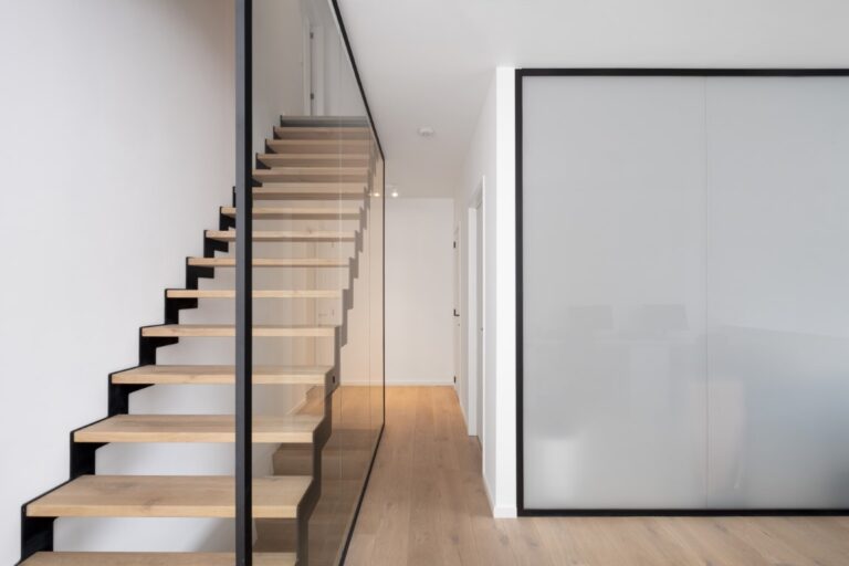 Een glazen wand als balustrade naast de trap en een glazen wand in verzuurd glas voor de badkamer.